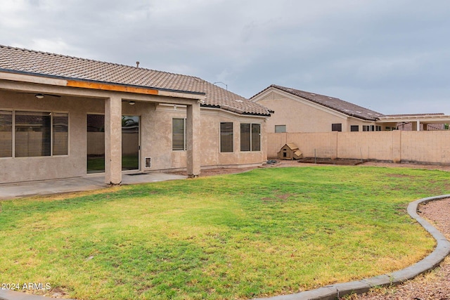 rear view of house featuring a patio, a tiled roof, a lawn, stucco siding, and a fenced backyard