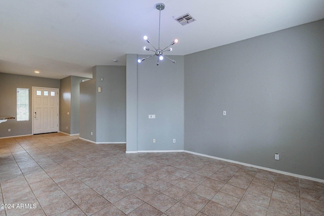 unfurnished room featuring an inviting chandelier, light tile patterned flooring, visible vents, and baseboards