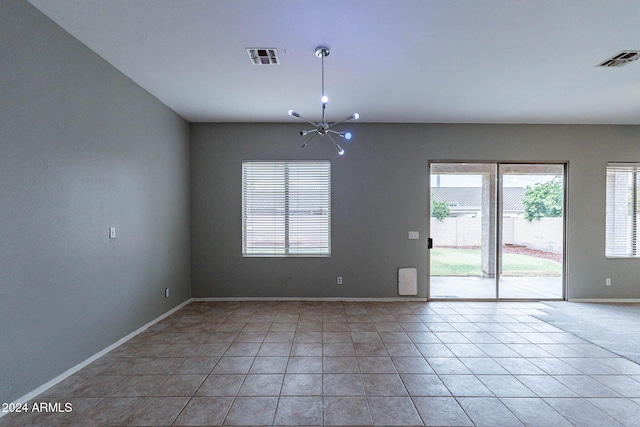 unfurnished room with a healthy amount of sunlight, visible vents, a notable chandelier, and baseboards