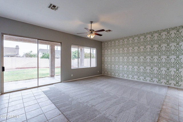 carpeted spare room with tile patterned flooring, ceiling fan, baseboards, and visible vents