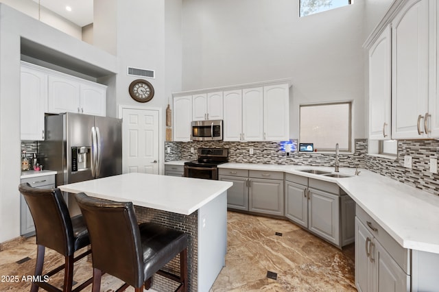 kitchen with sink, gray cabinetry, a kitchen breakfast bar, a center island, and stainless steel appliances