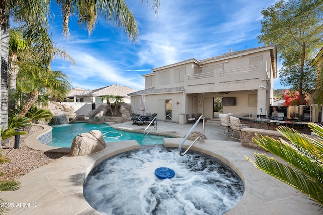 view of swimming pool featuring a bar, pool water feature, an in ground hot tub, and a patio area