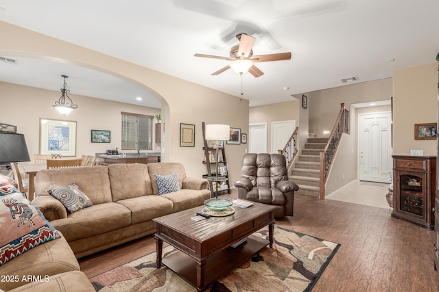 living room with arched walkways, visible vents, stairway, hardwood / wood-style floors, and baseboards