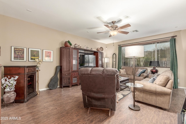 living area with ceiling fan, wood finished floors, visible vents, and baseboards