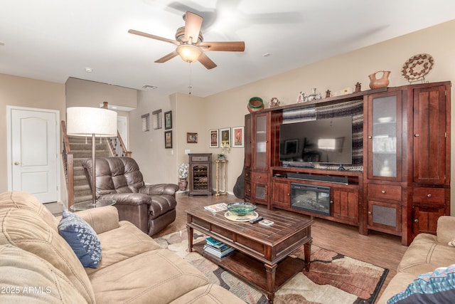 living area with light wood-style floors, ceiling fan, stairs, and visible vents