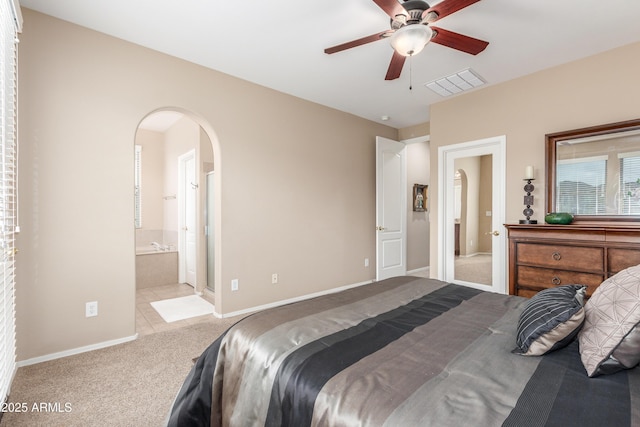 bedroom with visible vents, arched walkways, baseboards, ensuite bathroom, and carpet floors