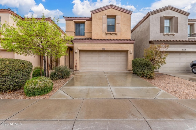 view of front of property with an attached garage, a tiled roof, concrete driveway, and stucco siding