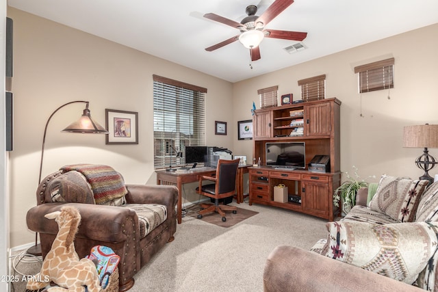 office space featuring light carpet, visible vents, and a ceiling fan