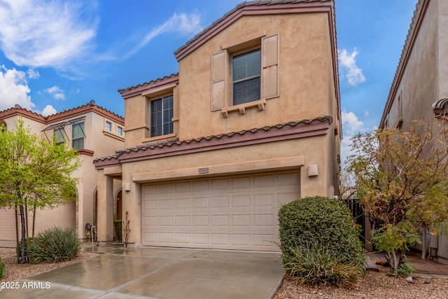 mediterranean / spanish home with an attached garage, a tile roof, concrete driveway, and stucco siding