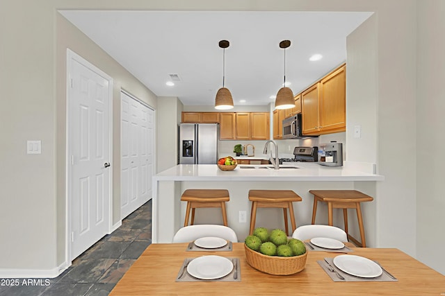 20121 N 76th St Unit 2021, Scottsdale, AZ 85255 - kitchen featuring appliances with stainless steel finishes, a peninsula, a sink, a kitchen breakfast bar, and dark stone finish floors