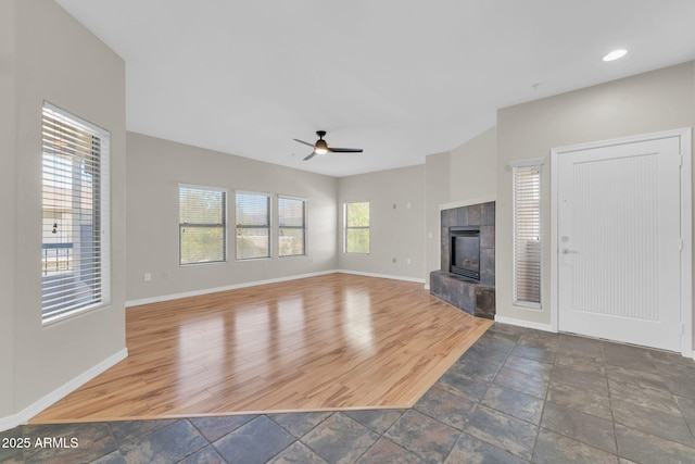 20121 N 76th St Unit 2021, Scottsdale, AZ 85255 - unfurnished living room featuring ceiling fan, baseboards, stone tile flooring, a tiled fireplace, and recessed lighting