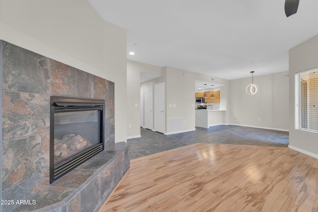 20121 N 76th St Unit 2021, Scottsdale, AZ 85255 - unfurnished living room with dark wood-type flooring, a tiled fireplace, baseboards, and recessed lighting