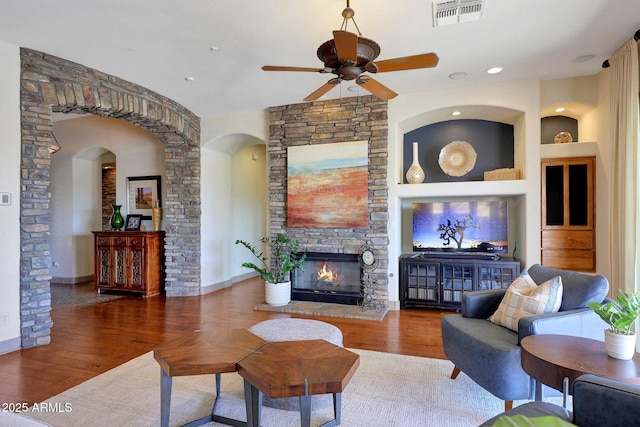 living area featuring built in shelves, a fireplace, visible vents, and wood finished floors