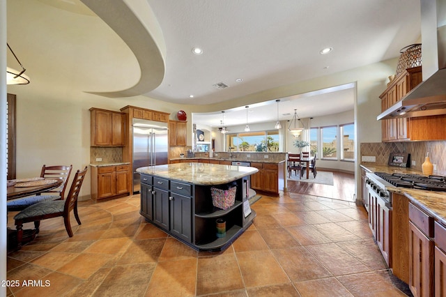 kitchen with open shelves, tasteful backsplash, appliances with stainless steel finishes, a peninsula, and wall chimney exhaust hood