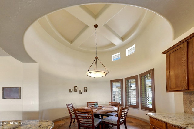 dining area with coffered ceiling, beamed ceiling, a towering ceiling, and baseboards