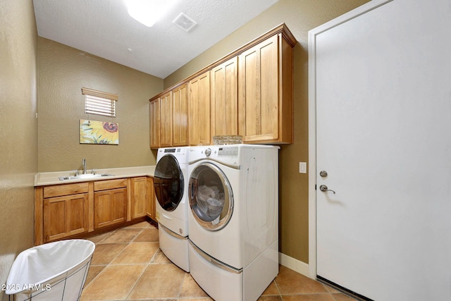 clothes washing area with cabinet space, visible vents, light tile patterned flooring, a sink, and independent washer and dryer