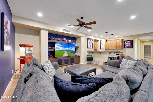 living area featuring baseboards, visible vents, arched walkways, light wood-style floors, and recessed lighting