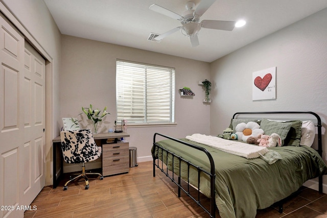 bedroom with baseboards, visible vents, a ceiling fan, wood finished floors, and a closet