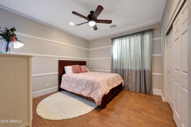 bedroom with a closet, wood finished floors, visible vents, and a ceiling fan