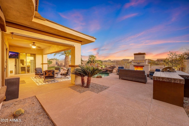 view of patio / terrace with an outdoor living space with a fireplace, an outdoor kitchen, and a fenced backyard