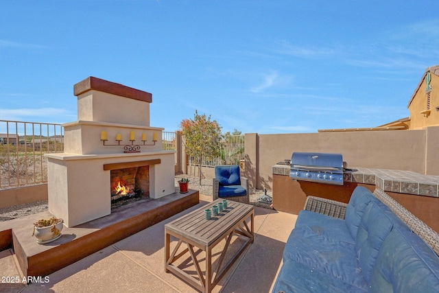 view of patio with an outdoor living space with a fireplace, area for grilling, and fence