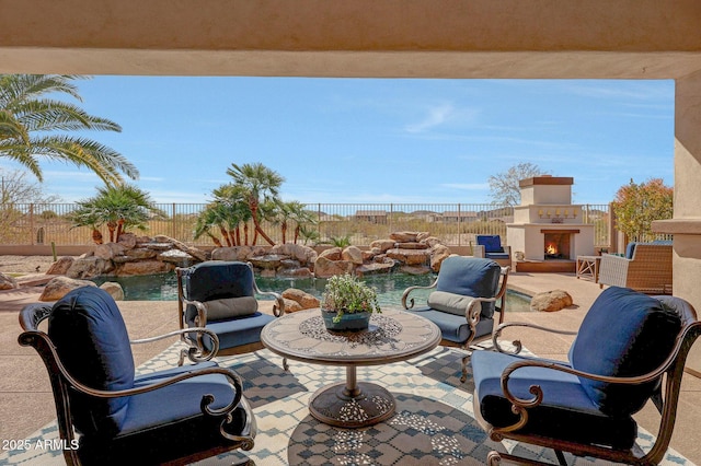 view of patio with a warm lit fireplace and a fenced backyard