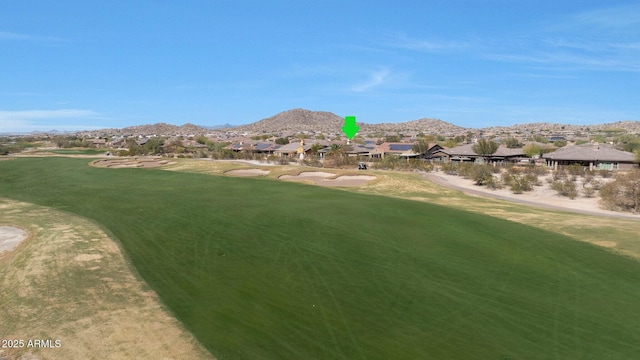 view of property's community featuring a lawn, golf course view, and a mountain view