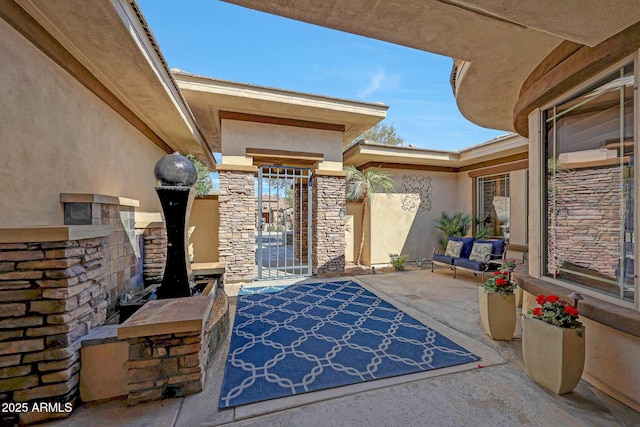 view of exterior entry with stone siding, a patio area, and stucco siding