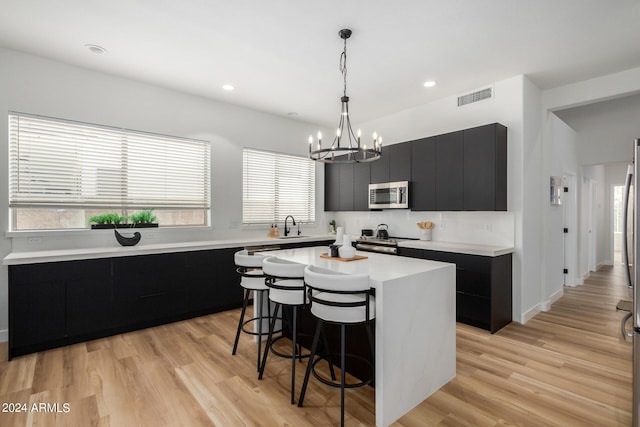 kitchen with a breakfast bar, sink, a kitchen island, stainless steel appliances, and hanging light fixtures