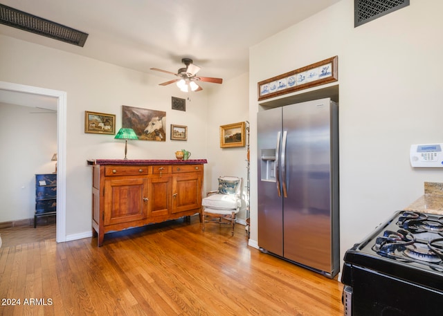 kitchen with black range with gas cooktop, stainless steel refrigerator with ice dispenser, light hardwood / wood-style floors, and ceiling fan