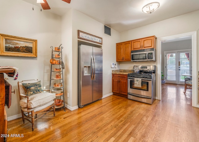 kitchen featuring ceiling fan, stainless steel appliances, and light hardwood / wood-style flooring