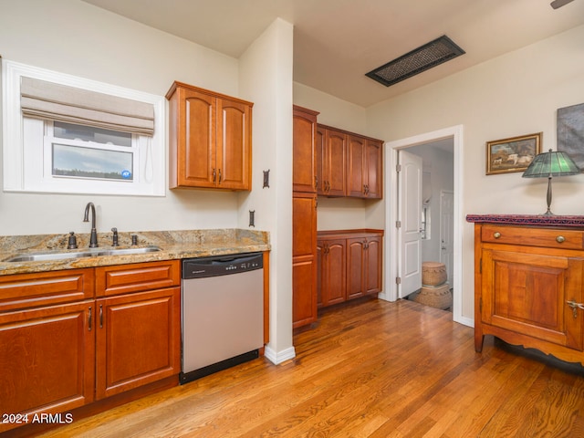 kitchen featuring light hardwood / wood-style floors, dishwasher, sink, and light stone counters