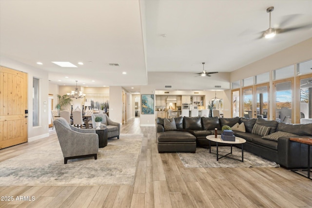 living room featuring ceiling fan with notable chandelier and light hardwood / wood-style floors