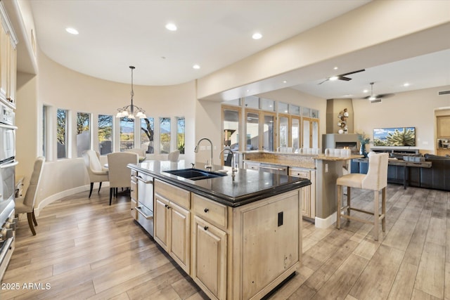 kitchen featuring a breakfast bar, pendant lighting, sink, a center island with sink, and light wood-type flooring