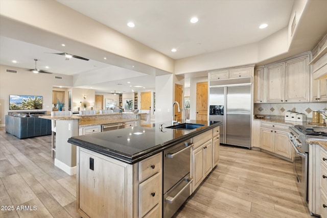 kitchen with sink, light hardwood / wood-style floors, high quality appliances, and a large island with sink