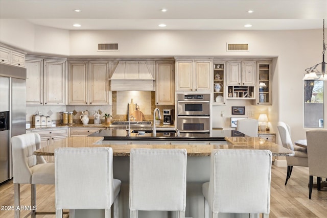 kitchen with a large island, pendant lighting, a breakfast bar, and premium range hood