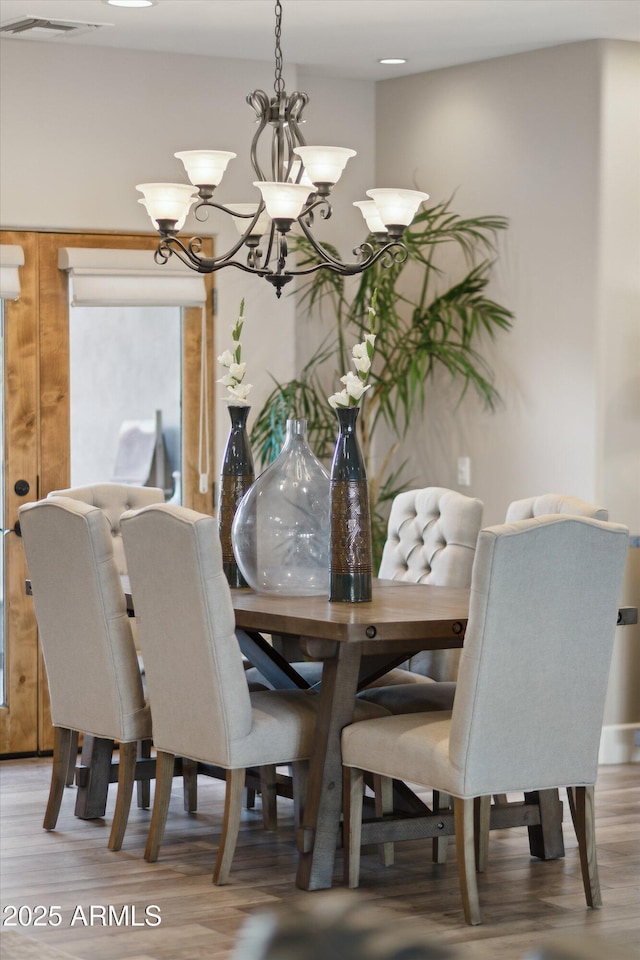 dining space with hardwood / wood-style floors and a chandelier