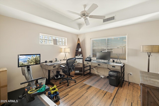 office featuring hardwood / wood-style flooring, ceiling fan, and a raised ceiling