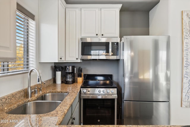 kitchen featuring white cabinetry, appliances with stainless steel finishes, light stone countertops, and sink