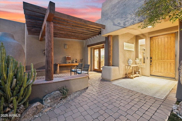 patio terrace at dusk featuring french doors and a pergola