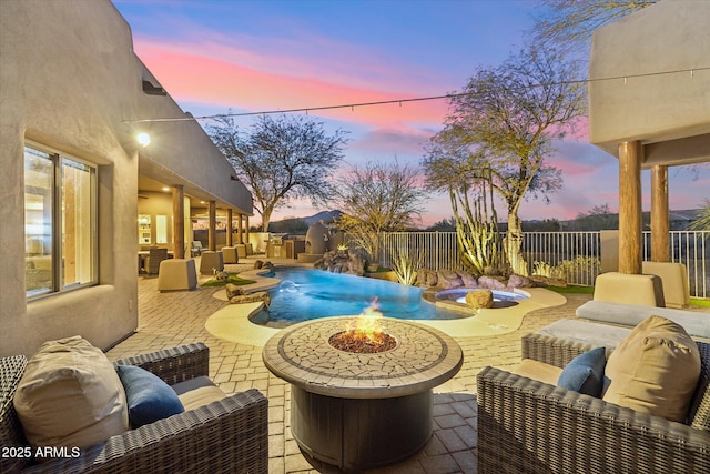 patio terrace at dusk featuring a fenced in pool, pool water feature, and an outdoor living space with a fire pit