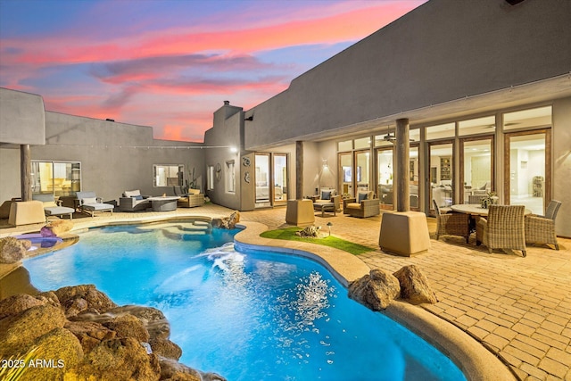 pool at dusk with outdoor lounge area and a patio