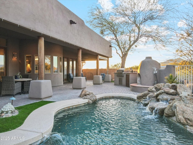 view of pool with pool water feature, an outdoor kitchen, grilling area, and a patio area