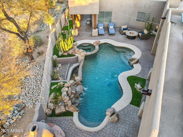 view of swimming pool with a patio, an outdoor living space with a fire pit, pool water feature, and an in ground hot tub