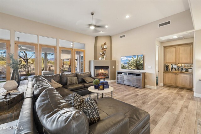 living room with a fireplace, light hardwood / wood-style floors, and ceiling fan