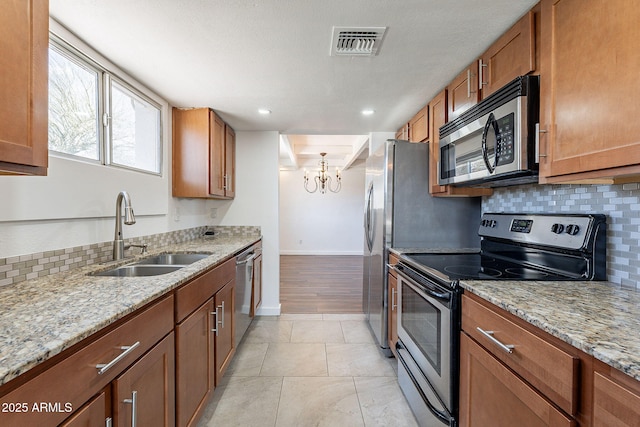 kitchen with brown cabinetry, visible vents, appliances with stainless steel finishes, and a sink