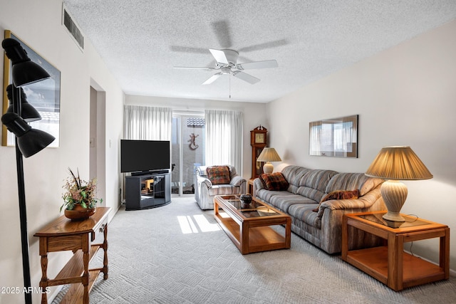 living room with a textured ceiling, carpet floors, and ceiling fan