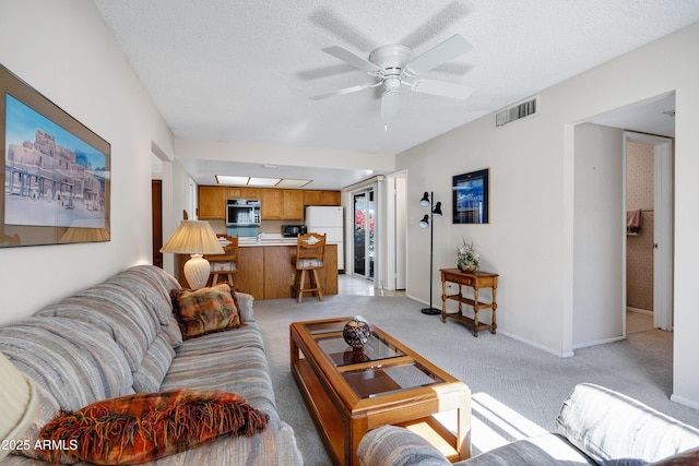 living room with light carpet, ceiling fan, and a textured ceiling