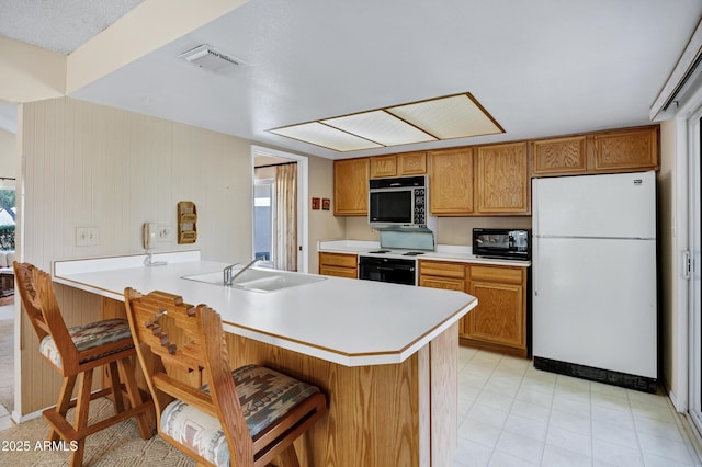 kitchen with electric stove, a breakfast bar, black microwave, kitchen peninsula, and white fridge