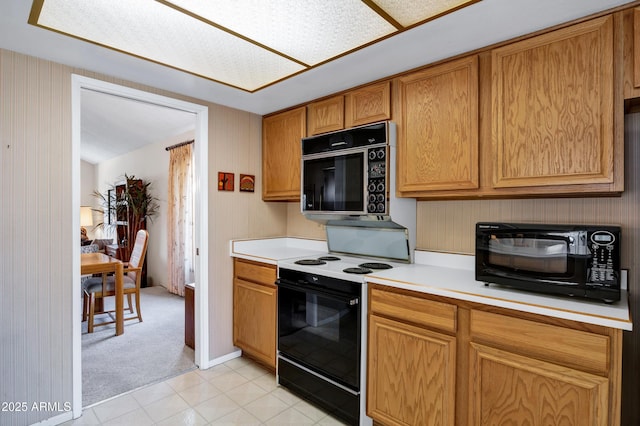 kitchen featuring wood walls, light carpet, and black appliances